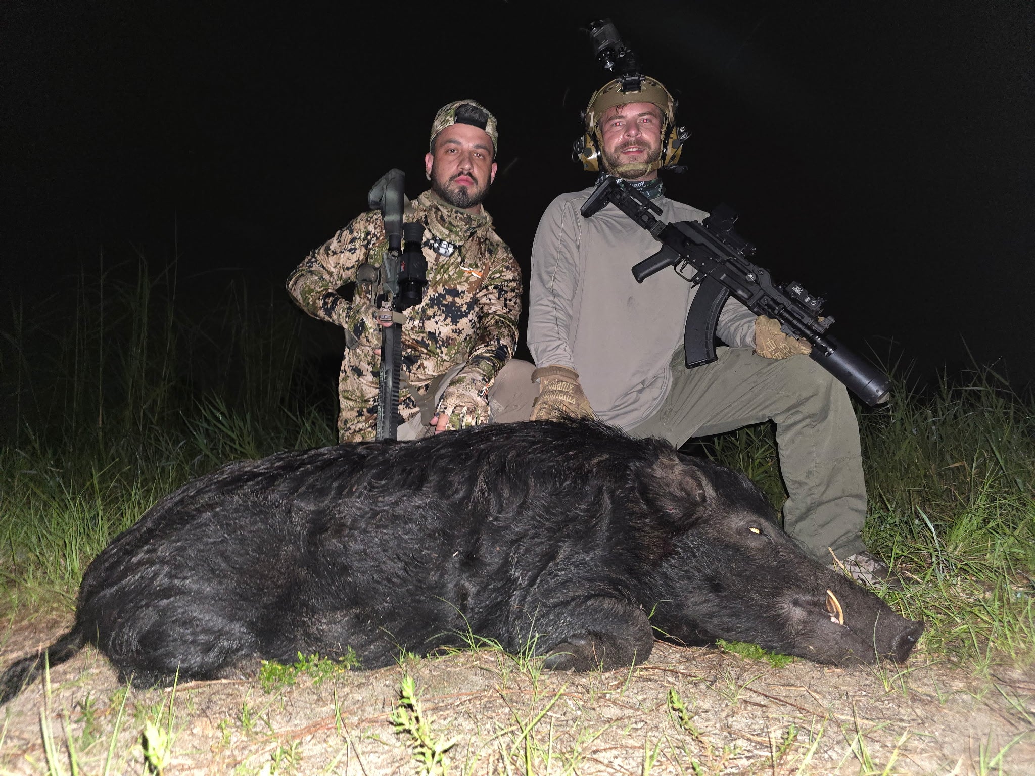 Two hunters with a mature boar after a thermal hunt
