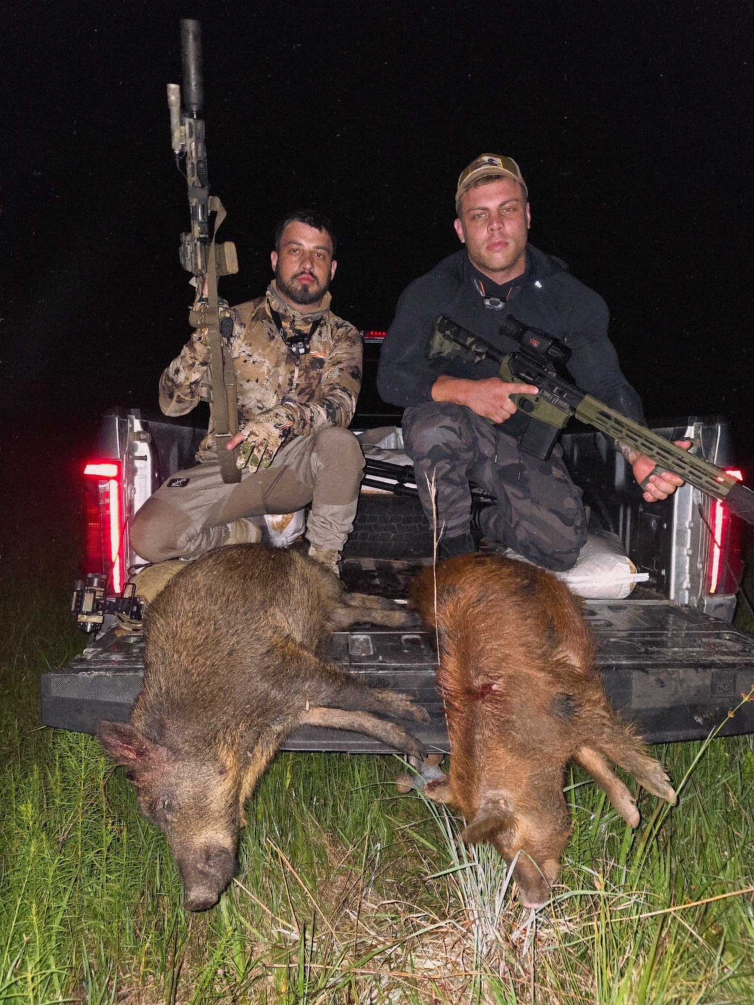Two hunters with two hogs after a night hunt